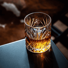 Crystal whiskey glass holding bourbon on a sleek table, perfect for cocktails or as gifts for men.