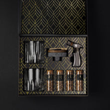 The Cocktail Smoker Kit displayed with glasses, wood chips, and smoker for whiskey smoking set.