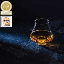 Crystal whiskey glass with amber drink showcasing elegance in barware for whiskey enthusiasts.