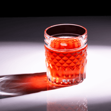 Elegant whiskey glass filled with a rich red cocktail, showcasing stylish design and fine crystal craftsmanship.