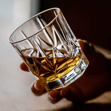 Hand holding a crystal whiskey glass filled with bourbon, showcasing elegant craftsmanship for barware.