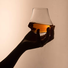 Hand holding a crystal whiskey nosing glass filled with whiskey, perfect for enhancing whiskey tasting experiences.