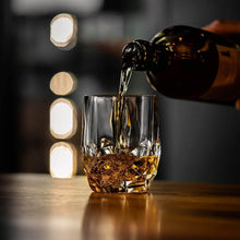 Pouring whiskey into a crystal glass from The Eco-Crystal Collection, ideal for chilling rocks and cocktails.
