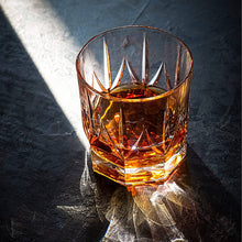 Imperial Eco Crystal whiskey glass filled with bourbon, showcasing elegant design and warmth in natural light.